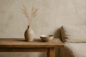 Ambiente com decoração Wabi-Sabi: mesa de madeira rústica com vaso artesanal, tigela imperfeita e sofá de linho, em cenário minimalista e natural.